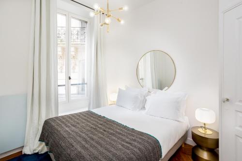 une chambre blanche avec un lit et un miroir dans l'établissement Habitat Parisien - 1BR-1BA - Bourse Montorgueil, à Paris