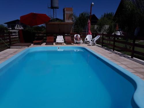 a blue swimming pool with chairs and umbrellas at Cabañas Namuncura in Colón