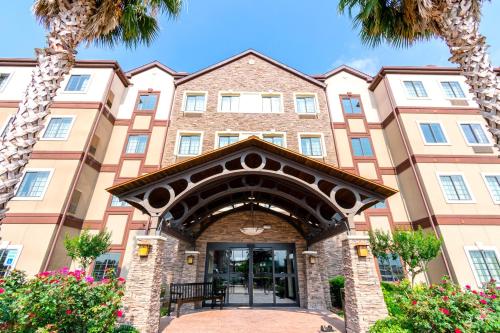 a large building with palm trees in front of it at Staybridge Suites Houston - IAH Airport by IHG in Houston