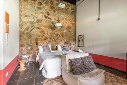um quarto com uma cama grande e uma parede de pedra em Selina Paraty em Paraty