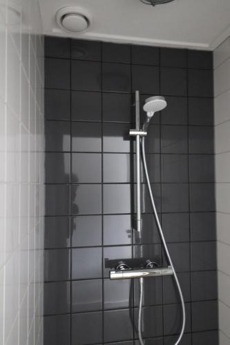 y baño con ducha y azulejos negros. en Sier aan Zee en Hollum