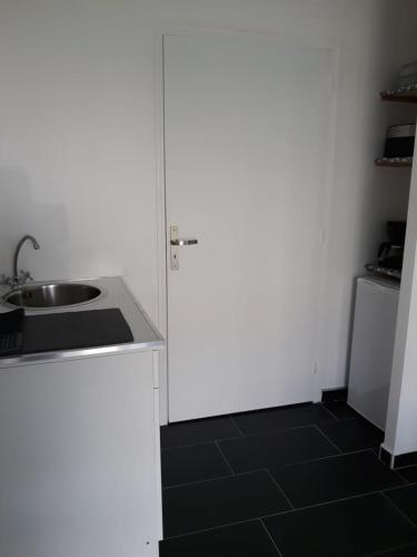a white kitchen with a sink and a refrigerator at Chambre cosy in Trois-Rivières
