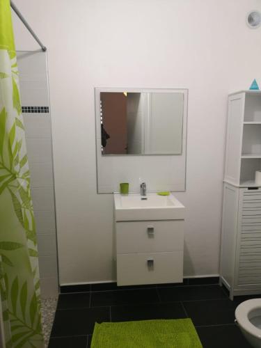 Baño blanco con lavabo y espejo en Chambre cosy, en Trois-Rivières