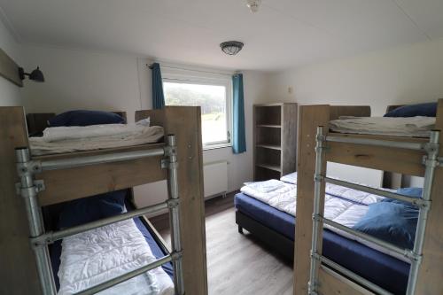 Zimmer mit 3 Etagenbetten und einem Fenster in der Unterkunft Sier aan Zee in Hollum