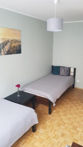 ヴロツワフにあるSand Apartmentのベッド2台とテーブルが備わる客室です。