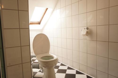 a bathroom with a toilet and a checkered floor at Vivo Apartments Herne in Herne