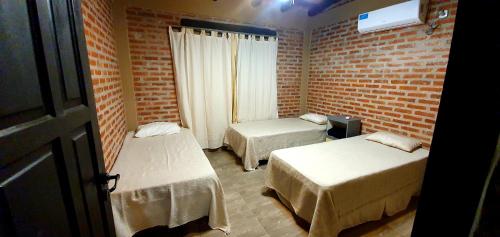 Una habitación con dos camas y una pared de ladrillo. en La Maina Uribe, en Uribelarrea