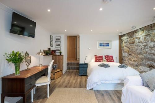 a bedroom with a bed and a desk and a tv at The Old Chandlery in Pittenweem