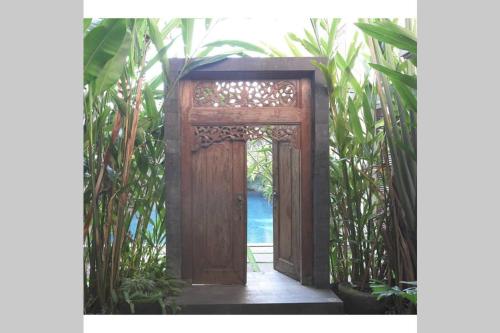uma porta de madeira aberta num jardim com plantas em Dreamy Loft em Malang