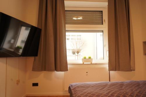 Schlafzimmer mit einem Fenster, einem Bett und einem TV in der Unterkunft Vivo Apartments at Hospitals in Herne