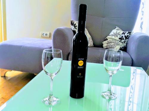 a bottle of wine and two glasses on a table at Lux Apartman Boris in Zlatibor