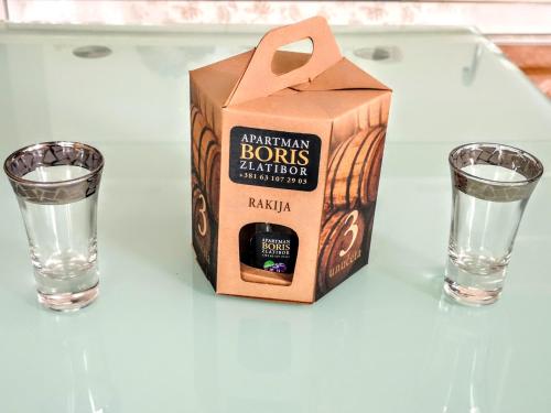 a box of bourbon and two glasses of water on a table at Lux Apartman Boris in Zlatibor