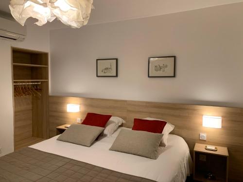 een slaapkamer met een wit bed met rode kussens bij Bel Appartement Terrasse 4 Étoiles Intra Muros in Aigues-Mortes