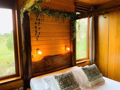a bedroom with a bed with a wooden wall and two windows at Herdade do Moinho Novo in Canha