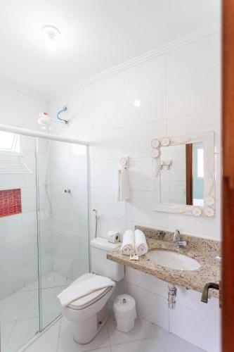 a white bathroom with a toilet and a sink at Pousada Pérola de Ubatuba in Ubatuba