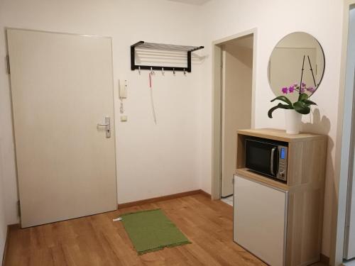 Zimmer mit einer Mikrowelle, einem Spiegel und einer Tür in der Unterkunft Apt next to Nuremberg central-station, Fair 10min in Nürnberg