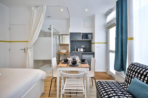 - un petit salon avec une table et un lit dans l'établissement cosy independant studio proche gare et jardin, à Paris