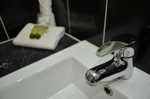a white sink sitting under a bathroom mirror at Airport Motel Brisbane in Brisbane
