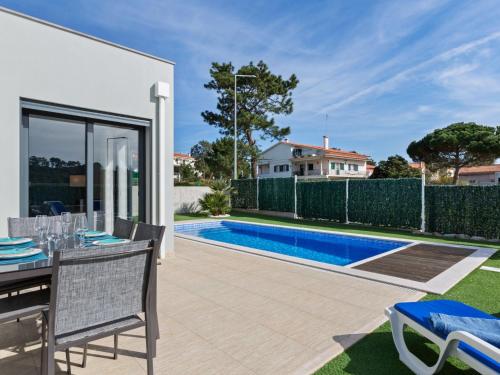 un patio con tavolo, sedie e piscina di Luxury villa with private heated pool a Foz do Arelho