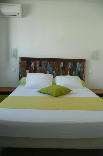 1 cama blanca grande con sábanas y almohadas verdes en Douceurs Caraïbes, Gîte Coco., en Bouillante