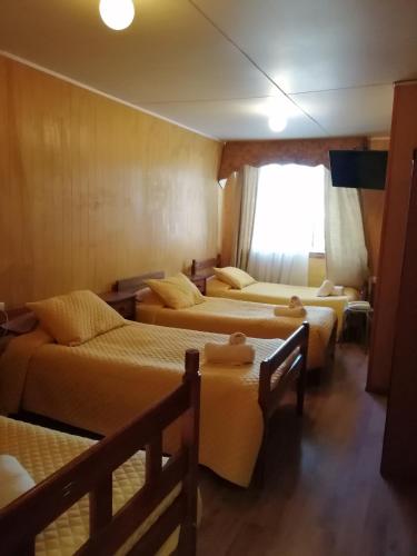 a room with four beds and a window at HOTEL CASAGRANDE con estacionamiento EXCLUSIVO in Valdivia