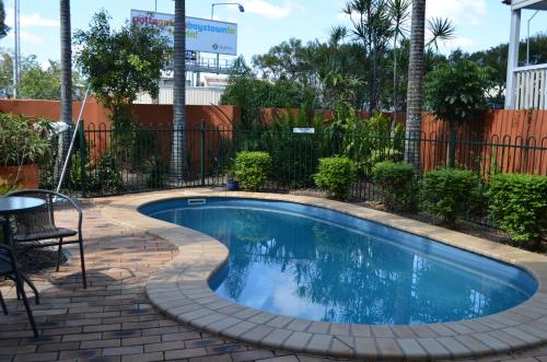 a small swimming pool with a brick patio and a fence at Airport Motel Brisbane in Brisbane