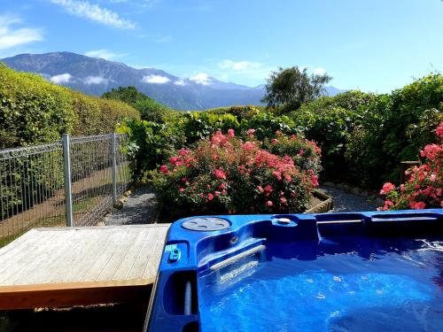 a hot tub in a garden with mountains in the background at Te Mahuru Retreat in Kaikoura