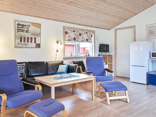グドイェムにある8 person holiday home in Gudhjemのリビングルーム(テーブル、青い椅子付)