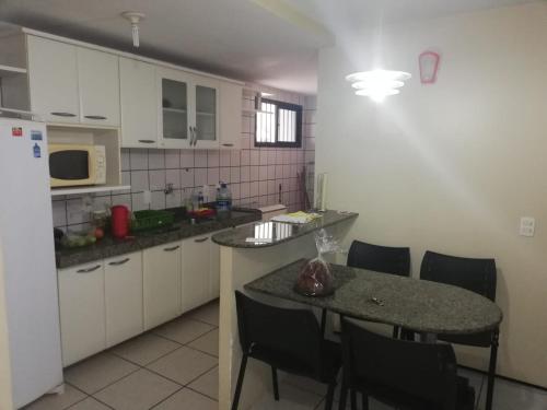 Apartamento em Fortaleza في فورتاليزا: مطبخ مع طاولة وكراسي وثلاجة
