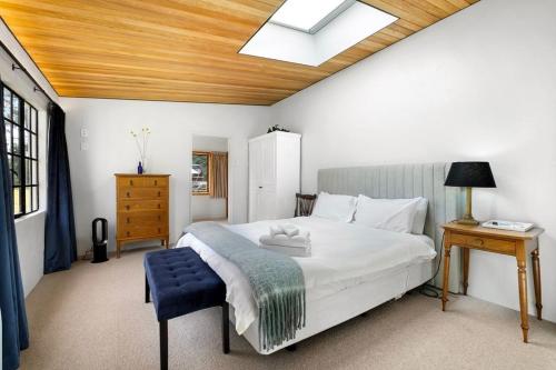 a bedroom with a white bed with a blue stool at Wanaka Stone Cottage - Wanaka Holiday Home in Wanaka