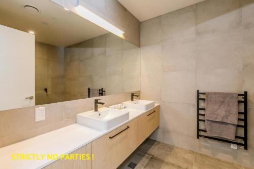 a bathroom with two sinks and a mirror at Acrossia Apartment Suites in Auckland