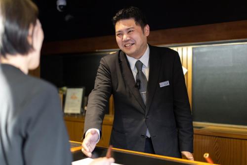 a man in a suit talking to a woman at Ishinoya Izunagaoka in Izunokuni