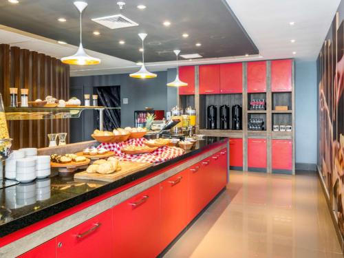 a kitchen with red cabinets and a counter with food at ibis Puerto Montt in Puerto Montt
