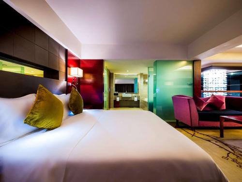 a hotel room with a large bed and a couch at Grand Mercure Xiamen Downtown-Free Welcome Fruit & Metro Station in Xiamen