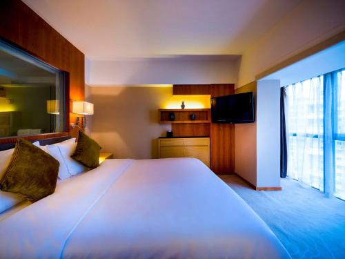 a hotel room with a large bed and a television at Grand Mercure Xiamen Downtown-Free Welcome Fruit & Metro Station in Xiamen