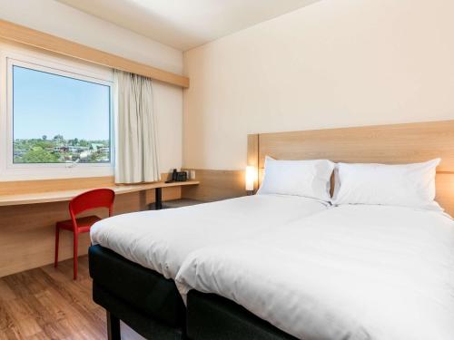 a hotel room with a large bed and a window at ibis Puerto Montt in Puerto Montt