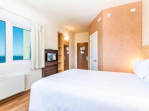 a bedroom with a large white bed and a window at ibis Puerto Montt in Puerto Montt