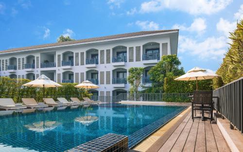 a hotel with a pool and chairs and umbrellas at Damrei Residence & Spa in Siem Reap