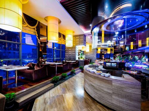 a restaurant with tables and chairs and a bar at Grand Mercure Xiamen Downtown-Free Welcome Fruit & Metro Station in Xiamen