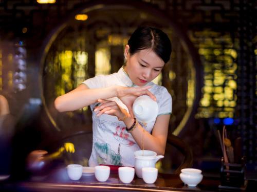 a woman is mixing cups on a table at Grand Mercure Xiamen Downtown-Free Welcome Fruit & Metro Station in Xiamen