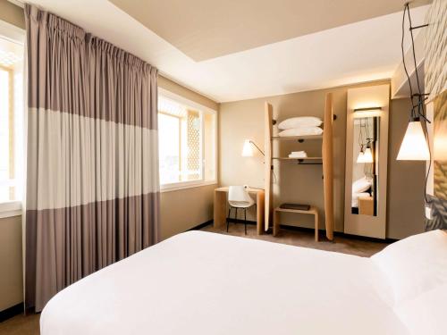 a bedroom with a large white bed and a window at ibis Lyon Carre De Soie in Vaulx-en-Velin