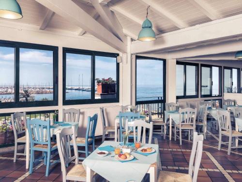 a restaurant with tables and chairs and windows at Sunbay Park Hotel in Civitavecchia