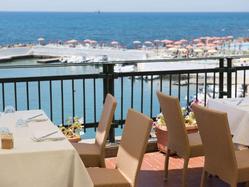 a restaurant with tables and chairs on a balcony with the beach at Sunbay Park Hotel in Civitavecchia