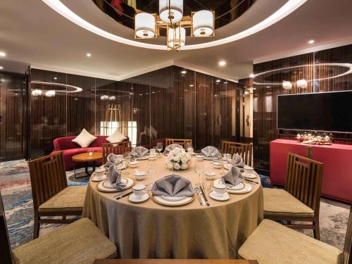 a dining room with a table with chairs and a tv at Novotel Shanghai Hongqiao in Shanghai