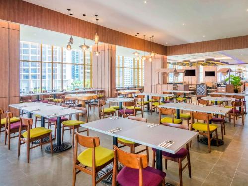 a restaurant with tables and chairs and windows at ibis Kuala Lumpur City Centre in Kuala Lumpur