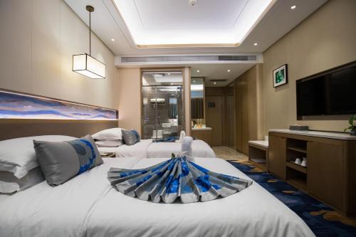 a hotel room with two beds and a flat screen tv at Kunming Golden Spring Hotel in Kunming