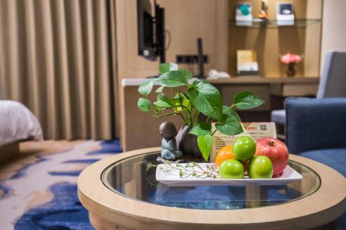 a table with a potted plant and fruit on it at Kunming Golden Spring Hotel in Kunming