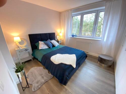 a bedroom with a bed with a blue blanket and a window at Luksusowa Willa pod Lasem, Otwock - Shared garden, sauna, wood hot tub! Hot tub seasonal! in Otwock