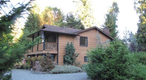 a large wooden house with a balcony in a yard at Shawnigan Lake Bed and Breakfast in Shawnigan Lake