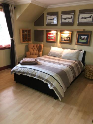 a large bed in a bedroom with pictures on the wall at Tranquil accommodation in a great location. in Lanark